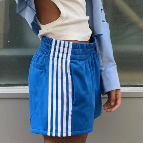 Person wearing blue shorts with white stripes, standing against a neutral background