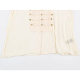 A close-up of a cream-colored garment featuring a central pleated panel adorned with gold-tone decorative buttons and ties, set against a plain white background.