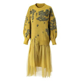 A yellow knit sweater dress featuring textured gray abstract patterns on the upper body and sleeves, with a layered tulle skirt overlay.