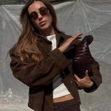 Woman holding a brown leather jacket against a plain background