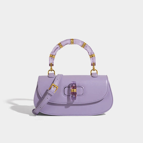 Lavender handbag with gold accents on a light gray background