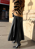 Person wearing a zebra print sweater and black pleated skirt on a city street.